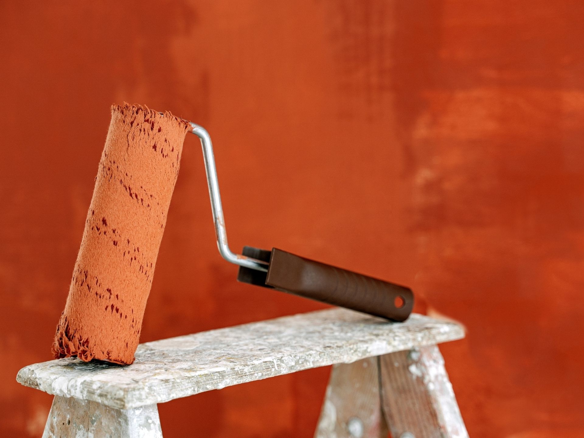 House interior painting in progress using a roller on a ladder during the paint application stage for smooth and even coverage.